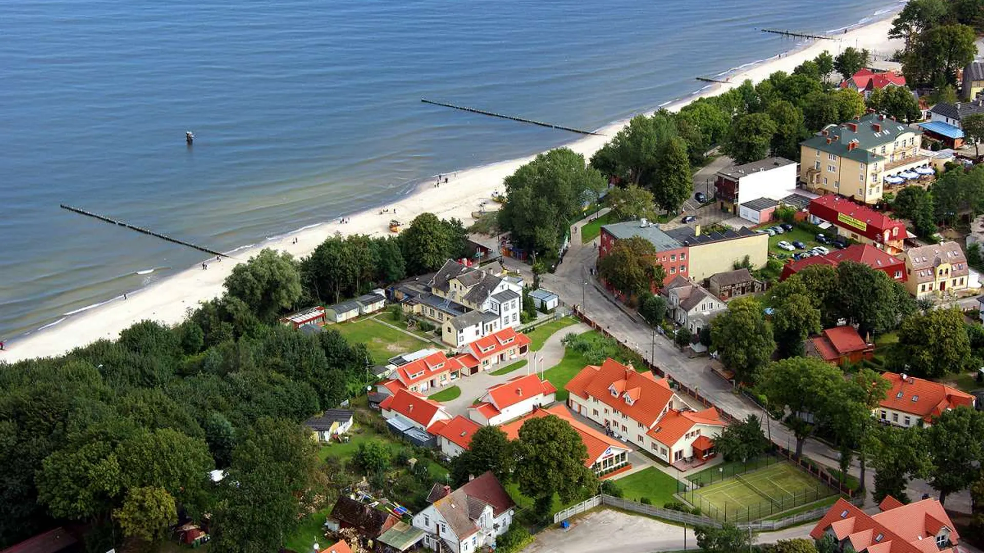 Aerial view of the Polonia holiday resort in Rewal: houses, greenery and the coastline.